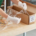 A person in gloves putting Western Plastics perforated film on a box of food.