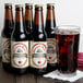 A close-up of several Reading Soda Works Creamy Red Birch soda bottles next to a glass of liquid.