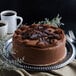 A Pellman triple chocolate cake on a white plate with a fork and a cup of coffee.