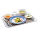 An Arcoroc blue glass soup plate with food on it.