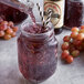 A glass jar of Reading Soda Works Grape Smoothie with a straw in it.