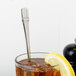 An iced tea glass with a lemon slice and a Oneida stainless steel spoon in it.