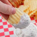 A close-up of a finger holding a Martin's Waffle Cut Potato Chip with dip.