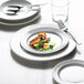 A white Arcoroc Candour porcelain service plate on a table with a fork on it.