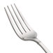 A close-up of a Oneida Astragal stainless steel table fork with a white handle.