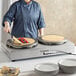 A woman using a Carnival King dual steel crepe maker on a table outdoors.