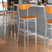 A group of Lancaster Table & Seating Boomerang Series bar stools with cherry wood seats and backs.