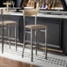 A metal bar stool with a driftwood seat and backrest, featuring a clear coat finish.