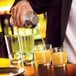 A bartender pouring liquid into Arcoroc old fashioned glasses on a counter.