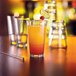 A highball glass filled with orange liquid and ice with a lemon wedge and red cherry on the rim.