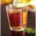 A customizable Arcoroc Stack Up double old fashioned glass filled with brown liquid and a mint leaf.