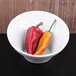 A white Elite Global Solutions Durango melamine bowl filled with red and yellow peppers.