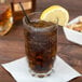 An Arcoroc highball glass of iced tea with a lemon wedge and a straw.