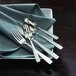 A close-up of Oneida Rio stainless steel salad/pastry forks on a table with other silverware.