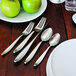 A table with a plate of apples and Oneida Sestina stainless steel dinner knives on it.