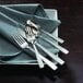 Oneida Rio stainless steel dinner fork on a table with other silverware.