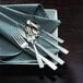 A close-up of Oneida Rio stainless steel serving spoons on a table with other silverware.