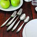 A table set with Oneida Sestina stainless steel teaspoons and a plate of green apples.