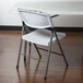 A white Lancaster Table & Seating plastic folding table with a white plastic chair on top.