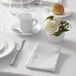 A white table setting with a Chef & Sommelier white bouillon cup on a saucer.