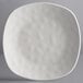 A close up of an Elite Global Solutions Off White square melamine plate with a textured surface.