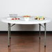 A Lancaster Table & Seating round folding table with food on it.