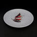 A round gray Elite Global Solutions melamine plate with red and black chili peppers on it.