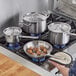 A person cooking with a Vigor stainless steel pan on a stove.