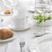 A white bone china saucer with two wells on a white table.