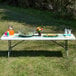 A Lancaster Table & Seating Granite White plastic folding table with food and a vase of flowers on it.