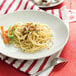 A Tuxton bright white coupe china plate with a plate of pasta and vegetables.