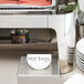 A white Tablecraft melamine table tent on a table with a hot dog tray.