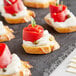 A piece of bread with roasted red pepper and cream cheese on a black surface.