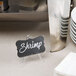 A Tablecraft clear acrylic card holder with a sign on a table.