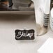 A Tablecraft clear acrylic card holder easel holding a sign on a hotel buffet counter.