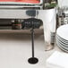 A Tablecraft black metal menu / card holder on a hotel buffet counter with a white menu card.