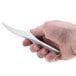 A hand holding a silver Winco shrimp deveiner in front of a white background.
