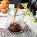 A coffee being poured into an Arcoroc glass mug.