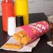 A Solo paper cup filled with chicken strips on a table with a ketchup bottle.