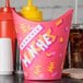 A pink Solo paper container with a design on it next to condiments and a yellow bottle with a pointy tip.