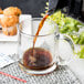 A cup of coffee being poured into an Arcoroc glass mug.