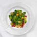 An Arcoroc white porcelain brunch plate with salad, grapes, and broccoli on it.