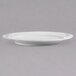 An Arcoroc white porcelain dinner plate with a rim on a gray surface.