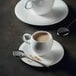 A white cup of coffee on a saucer with a Chef & Sommelier stainless steel coffee spoon.