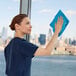 A person cleaning a window with a blue Rubbermaid HYGEN r-40 16" x 16" recycled microfiber cloth.