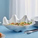 A white shell shaped bowl filled with shrimp salad on a table.