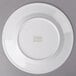 An Arcoroc white porcelain salad plate with a green logo on it.