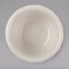 A close-up of a Hall China flared ivory ramekin on a gray surface.