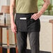 A man wearing a black Chef Revival waist apron with pockets.