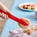 A person using a Cambro red scallop grip tong to pick up a cookie.